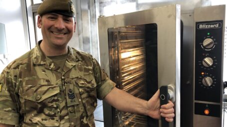 Man in uniform stood by a steam oven