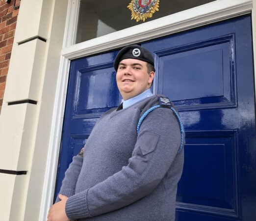 Cadet Callum McGrath standing in his air cadet uniform smiling in front of a blue door