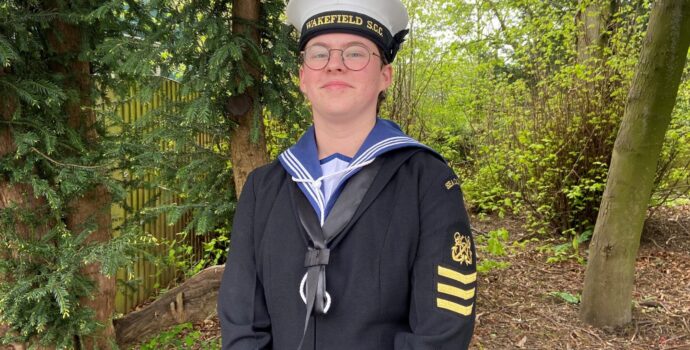 Sea cadet Talitha Ridley wearing her uniform stands in front of some greenery